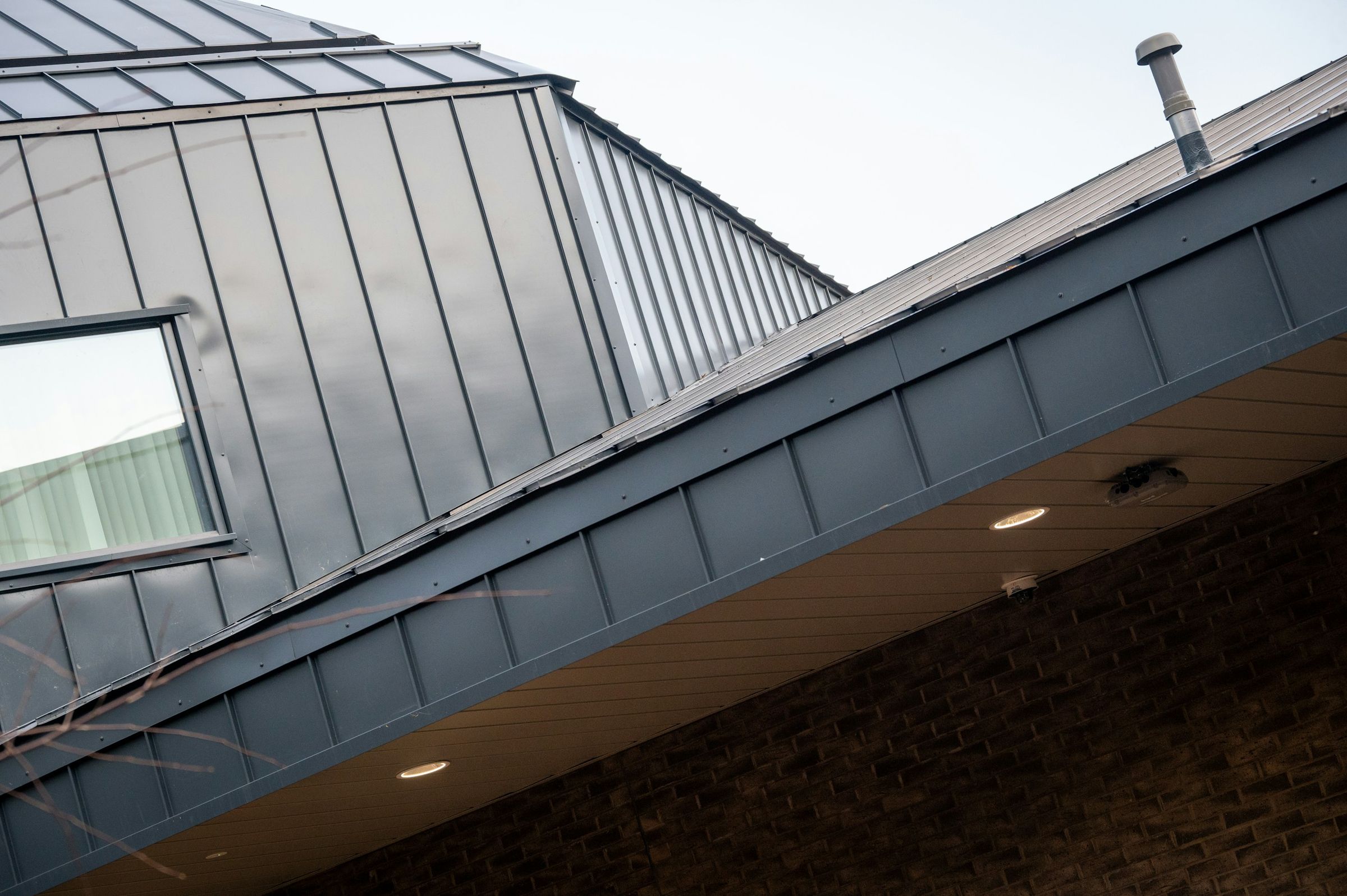 Dach und Gaube in anthrazitfarbenem Stehfalz über einer Klinkerfassade